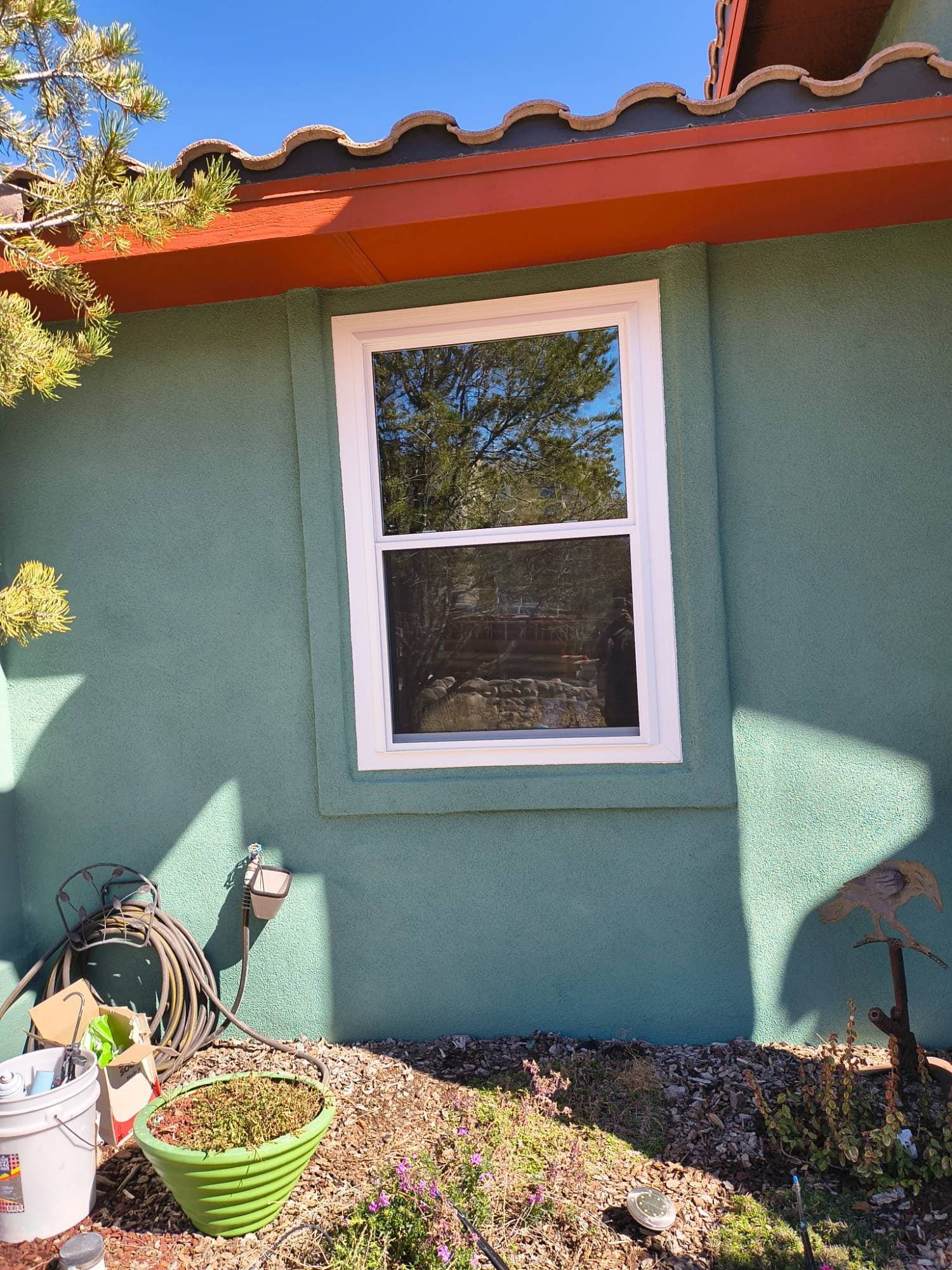Completed double-hung window replacement, green stucco home
